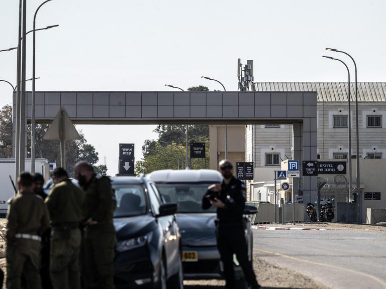 Blick auf den Militärstützpunkt Sde Teiman, nahe dem Gazastreifen. Im Vordergrund bewaffnete israelische Soldaten, im Hintergrund der Gebäudekomplex.