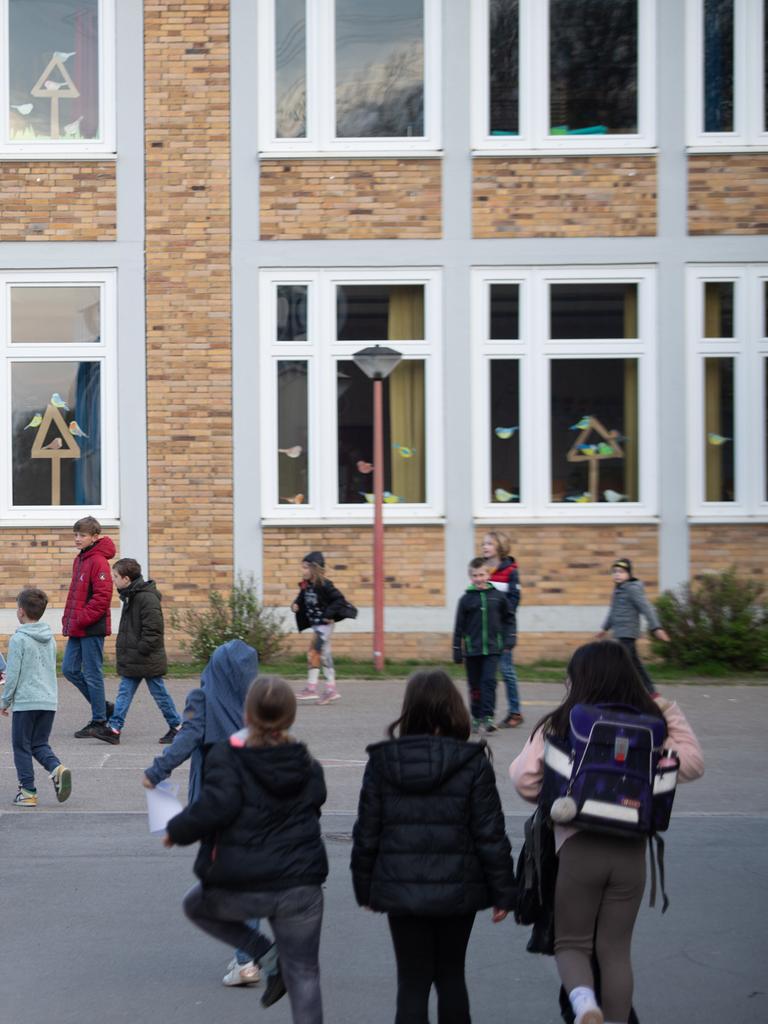 Mehrere Schüler laufen über einen Pausenhof zum Schulgebäude.