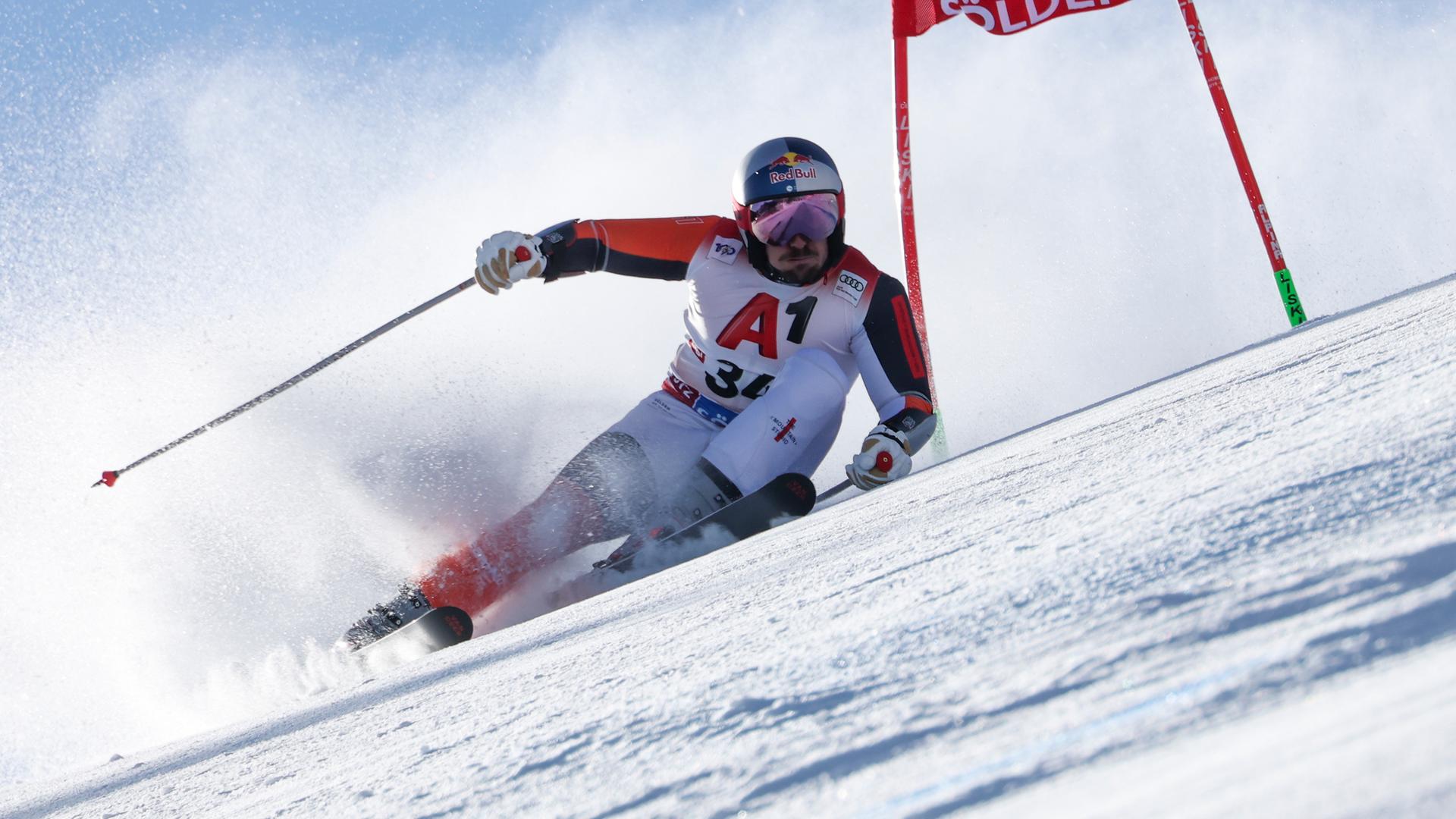 Marcel Hirscher fährt mit starker Schräglage eng an einem Tor vorbei und bläst dabei die Backen auf.