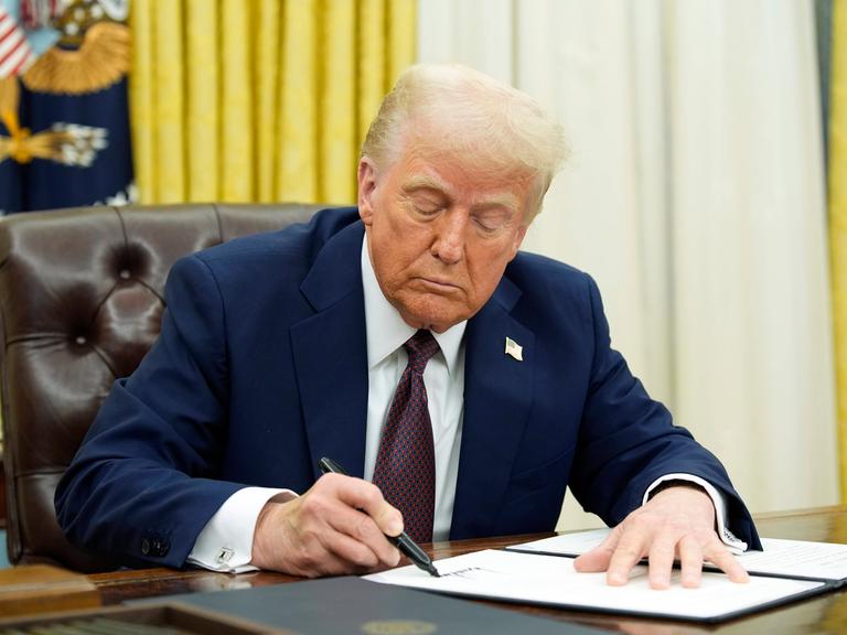 Das Foto zeigt Donald Trump an seinem Schreib-Tisch in seinem Büro. 