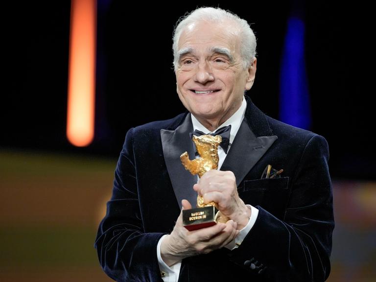Martin Scorsese hält den Goldenen Ehrenbären in der Hand und lacht.