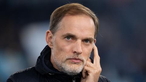 FC-Bayern-Trainer Thomas Tuchel schaut nachdenklich vor dunklem Hintergrund. 