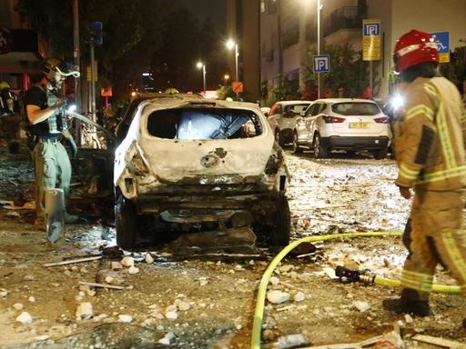 Feuerwehrleute in Tel Aviv untersuchen ein zerstörtes Auto nach einem Hamas-Raketenangriff in der Innenstadt.