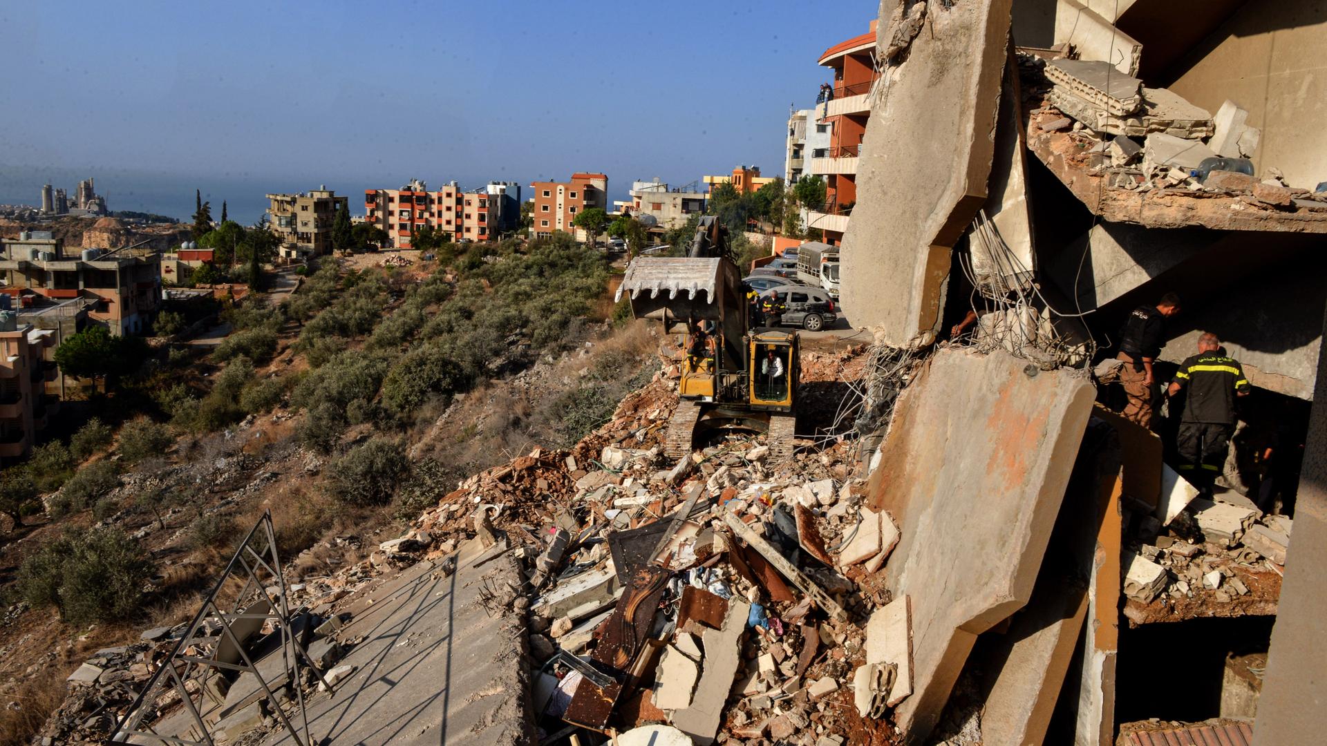 Libanon, Bardschaa: Rettungskräfte entfernen mit einem Bagger die Trümmer eines zerstörten Gebäudes, das bei einem israelischen Luftangriff getroffen wurde, während sie nach Opfern suchen. 