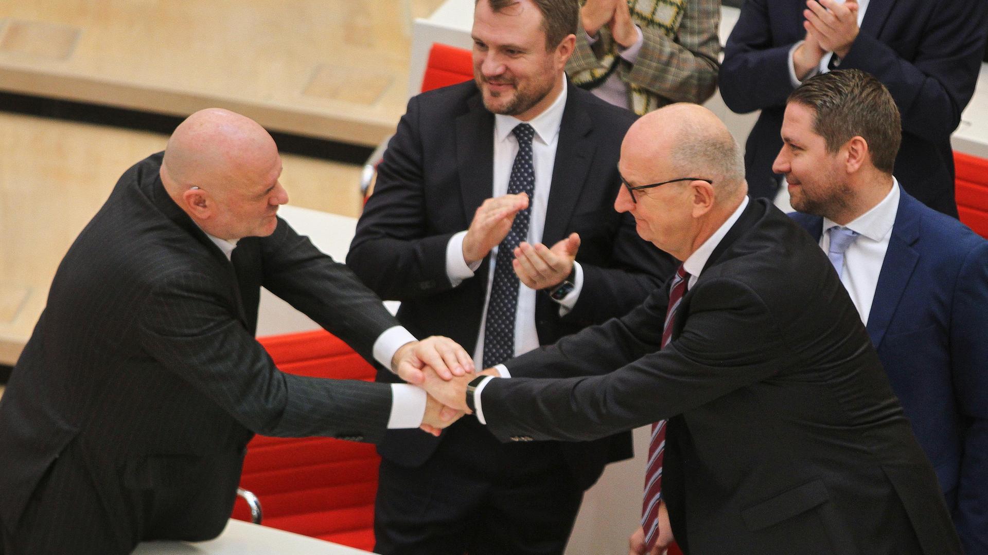 Robert Crumbach und Dietmar Woidke gratulieren einander und schütteln sich über einen Tisch hinweg beide Hände.