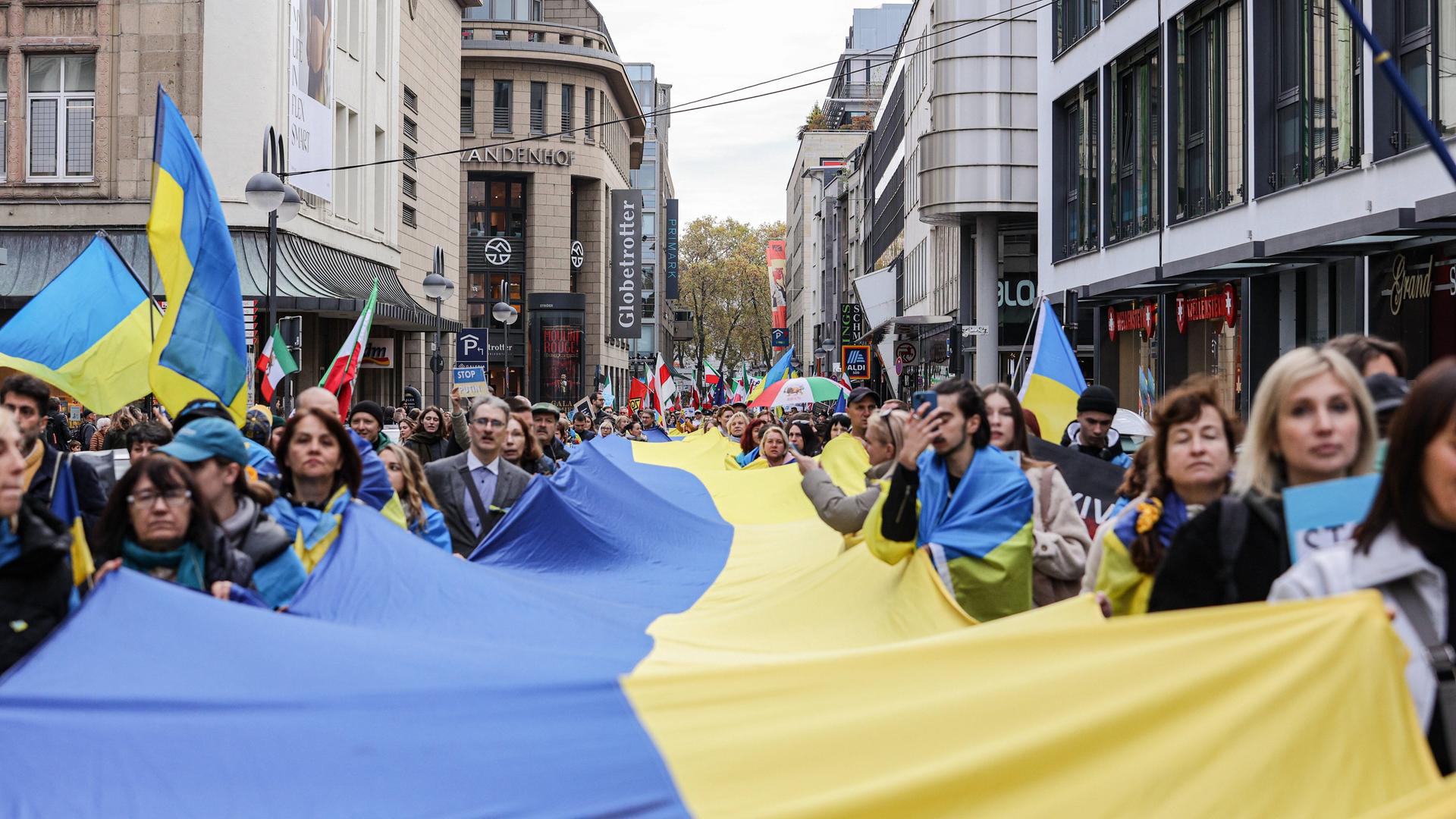 Tausende demonstrieren in Köln für Menschenrechte, Gleichberechtigung und gegen Krieg. Demonstrierende tragen eine große Ukraine-Fahne. (05.11.2022)