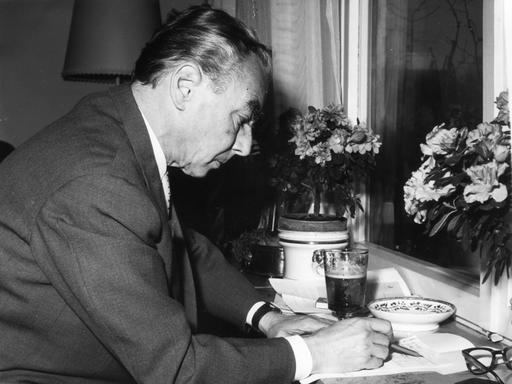 Erich Kästner sitzt an einem kleinen Tisch. Das Bild zeigt den Schriftsteller im jahr 1959