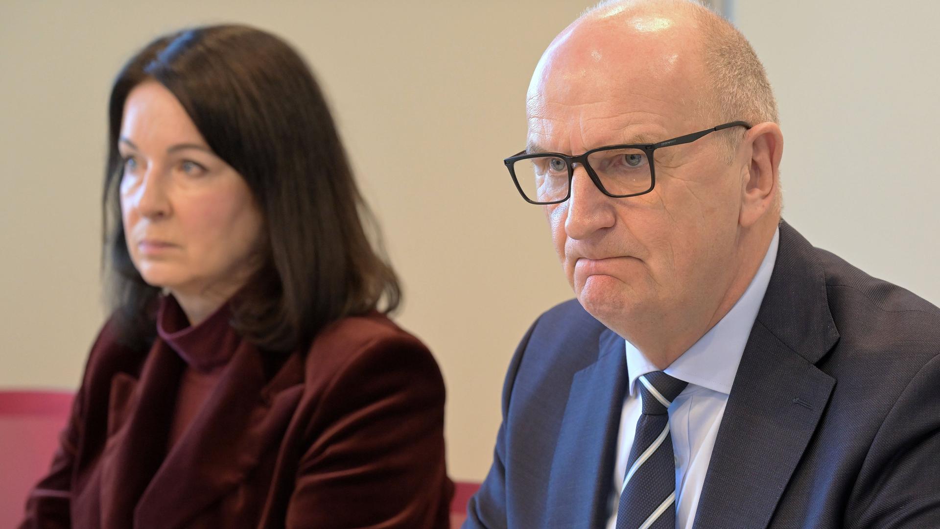 Britta Müller von der Partei BSW und Ministerpräsident Woidke von der SPD sitzen nebeneinander bei einer Presse-Konferenz. Beide schauen mürrisch.