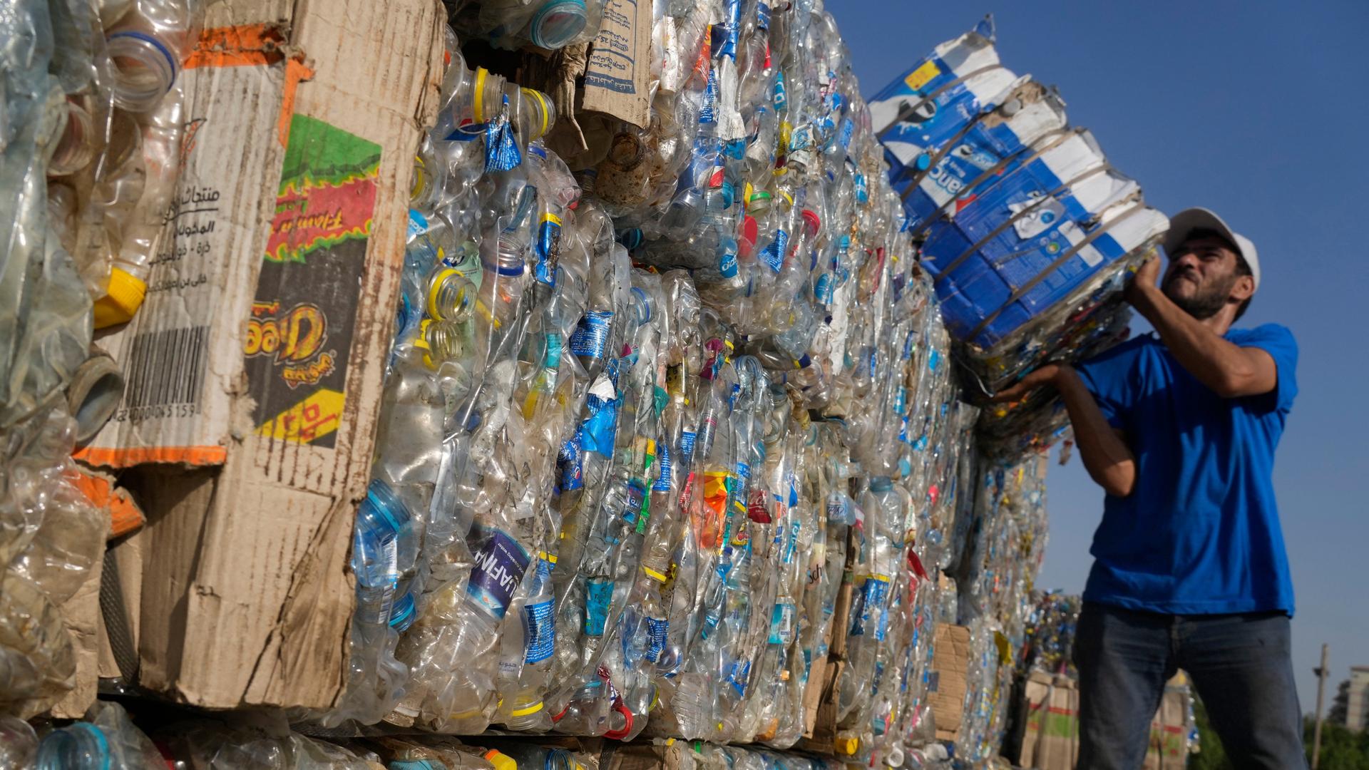 Das Foto zeigt einen Mitarbeiter der Initiative "Verynile". Er trägt gepresste Plastikflaschen, die von Freiwilligen und Fischern im Nil gesammelt wurden, um eine Plastikpyramide vor dem Weltsäuberungstag zu errichten.