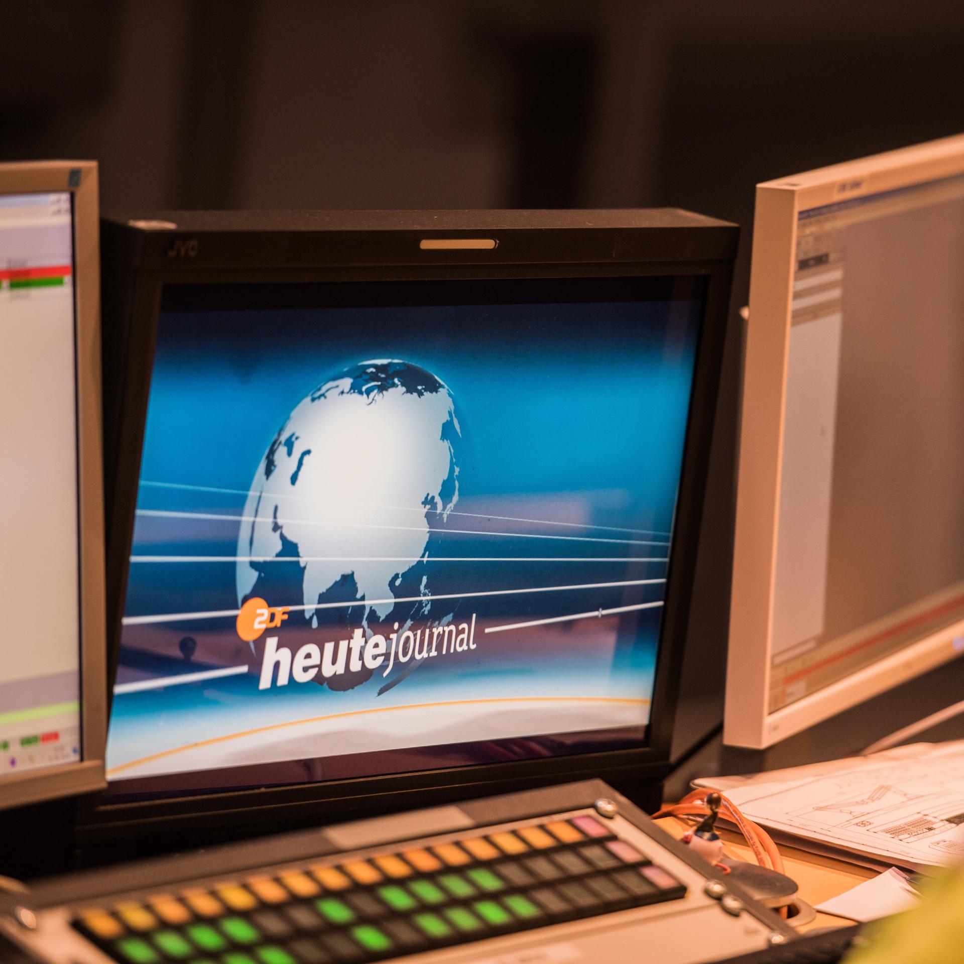 Auf einem Bildschirm ist das Logo des "heute journal" zu sehen, eine Weltkugel vor blauem Grund.