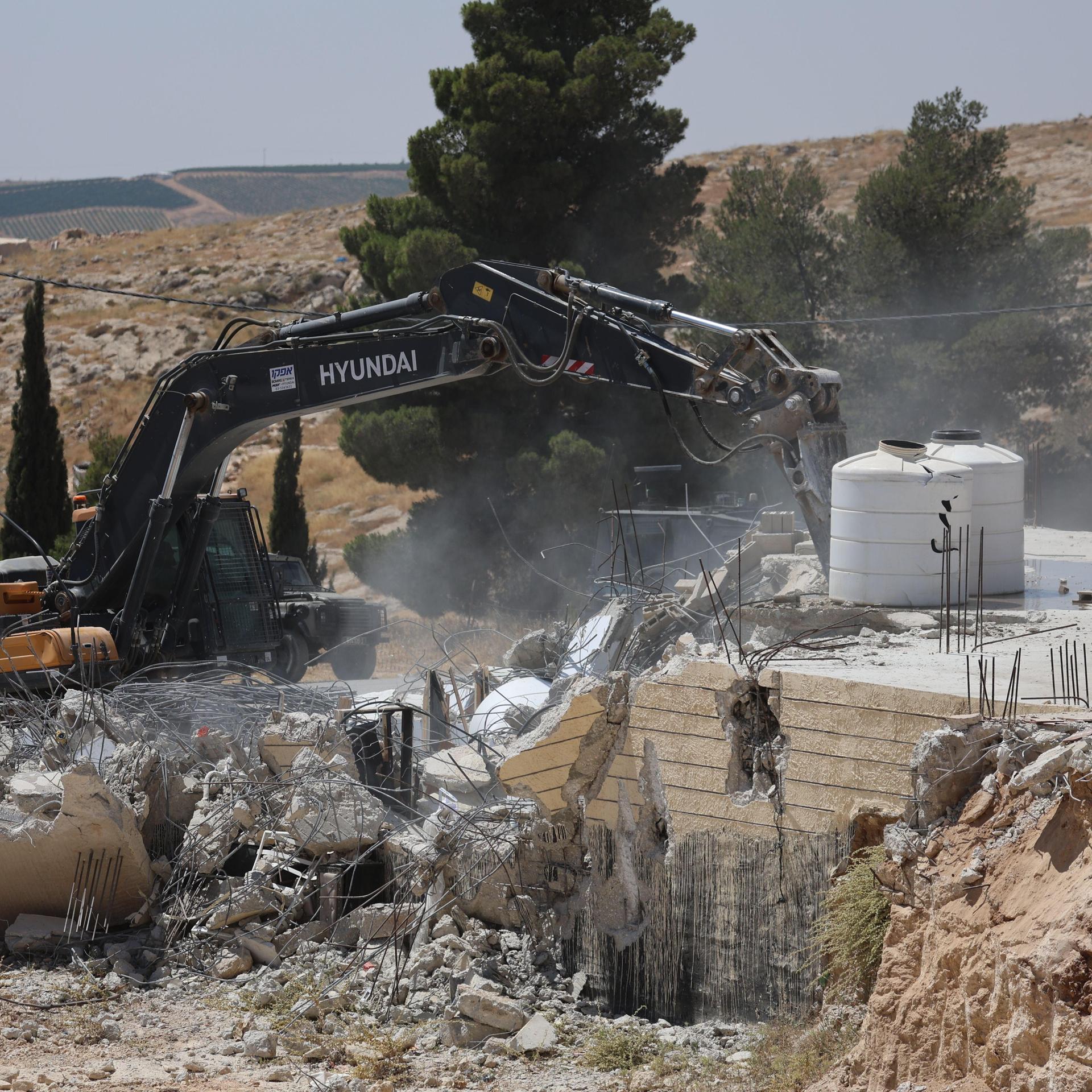 Ein palästinensisches Haus wird von israelischen Siedlern mit einem Bagger zerstört.