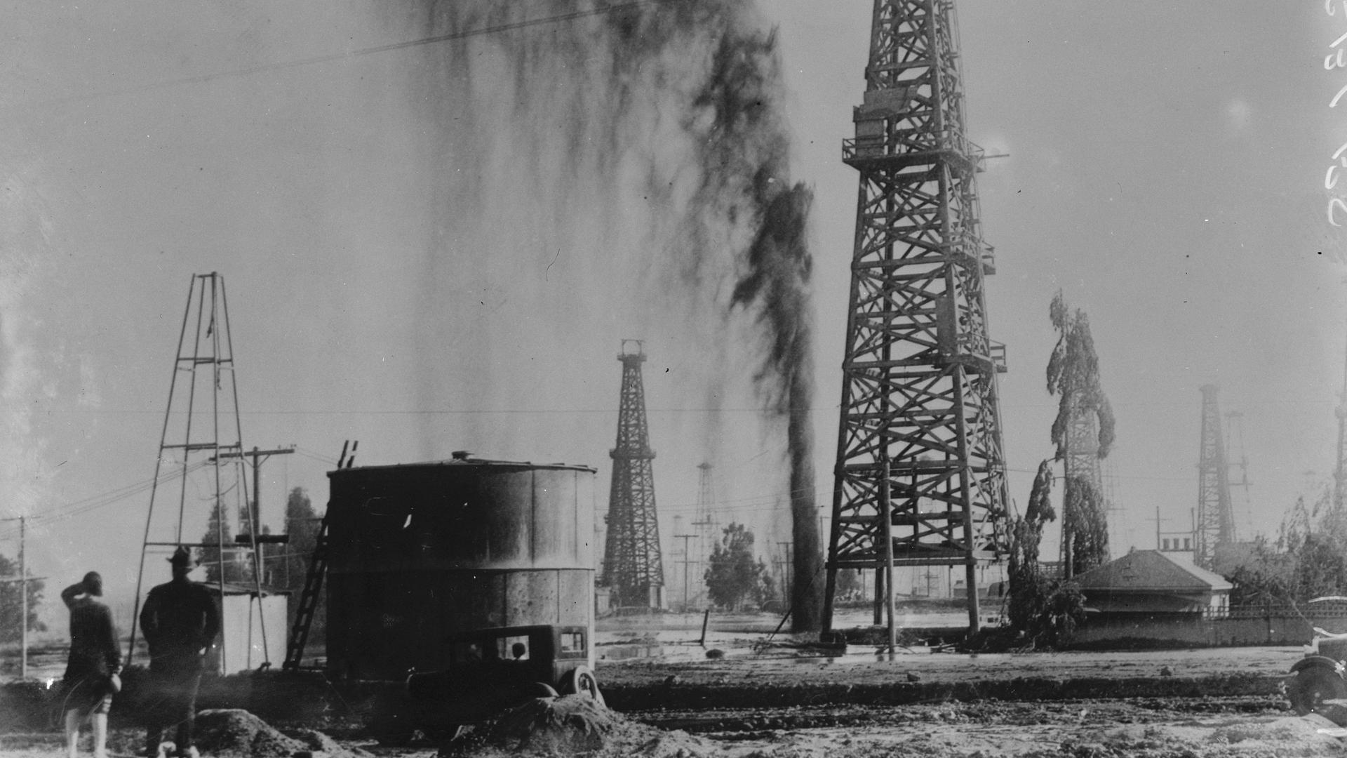 Eine Ölförderanlage in Los Angeles, Kalifornien. Neben einem Ölförderturm spritzt Öl aus dem Boden.