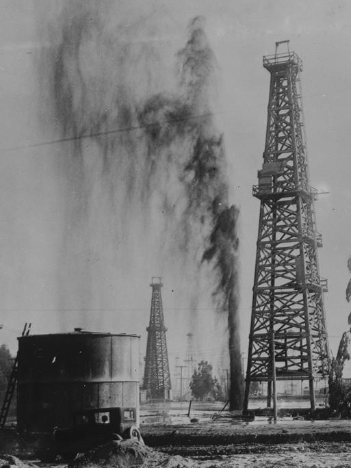 Eine Ölförderanlage in Los Angeles, Kalifornien. Neben einem Ölförderturm spritzt Öl aus dem Boden.