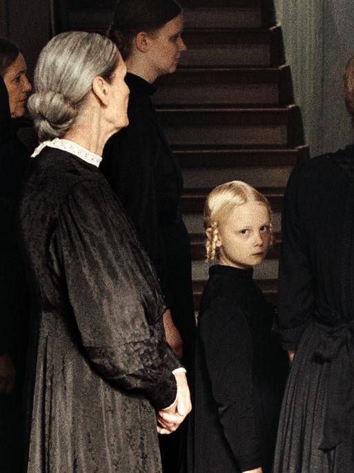 Das Foto zeigt eine Szene aus dem Spielfilm "In die Sonne schauen", in der Alma, gespielt von Hanna Heckt (Mitte), mit ihrer Familie an einer Totenfeier teilnimmt.
