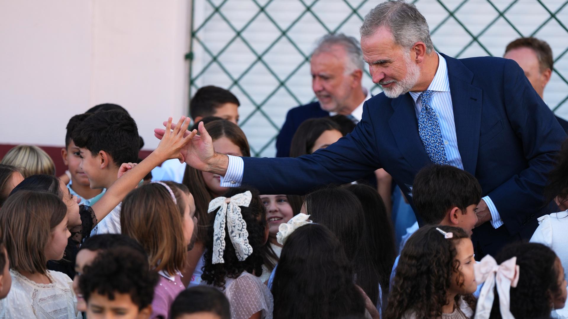 Spaniens König Felipe an einer Schule in Ceuta, inmitten von Kindern. Ein Junge und der König strecken sich die Hand entgegen. Spaniens König Felipe an einer Schule in Ceuta, inmitten von Kindern. Ein Junge und der König strecken sich die Hand entgegen.