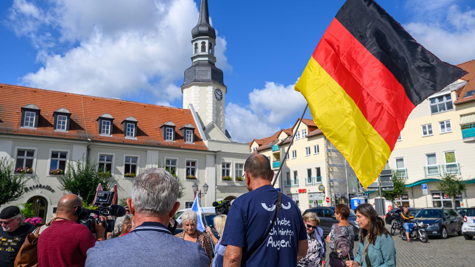 Einige Teilnehmer einer Protestveranstaltung gegen die Bürgermeisterin der Stadt Spremberg im Landkreis Spree-Neiße haben sich auf dem Marktplatz versammelt.
