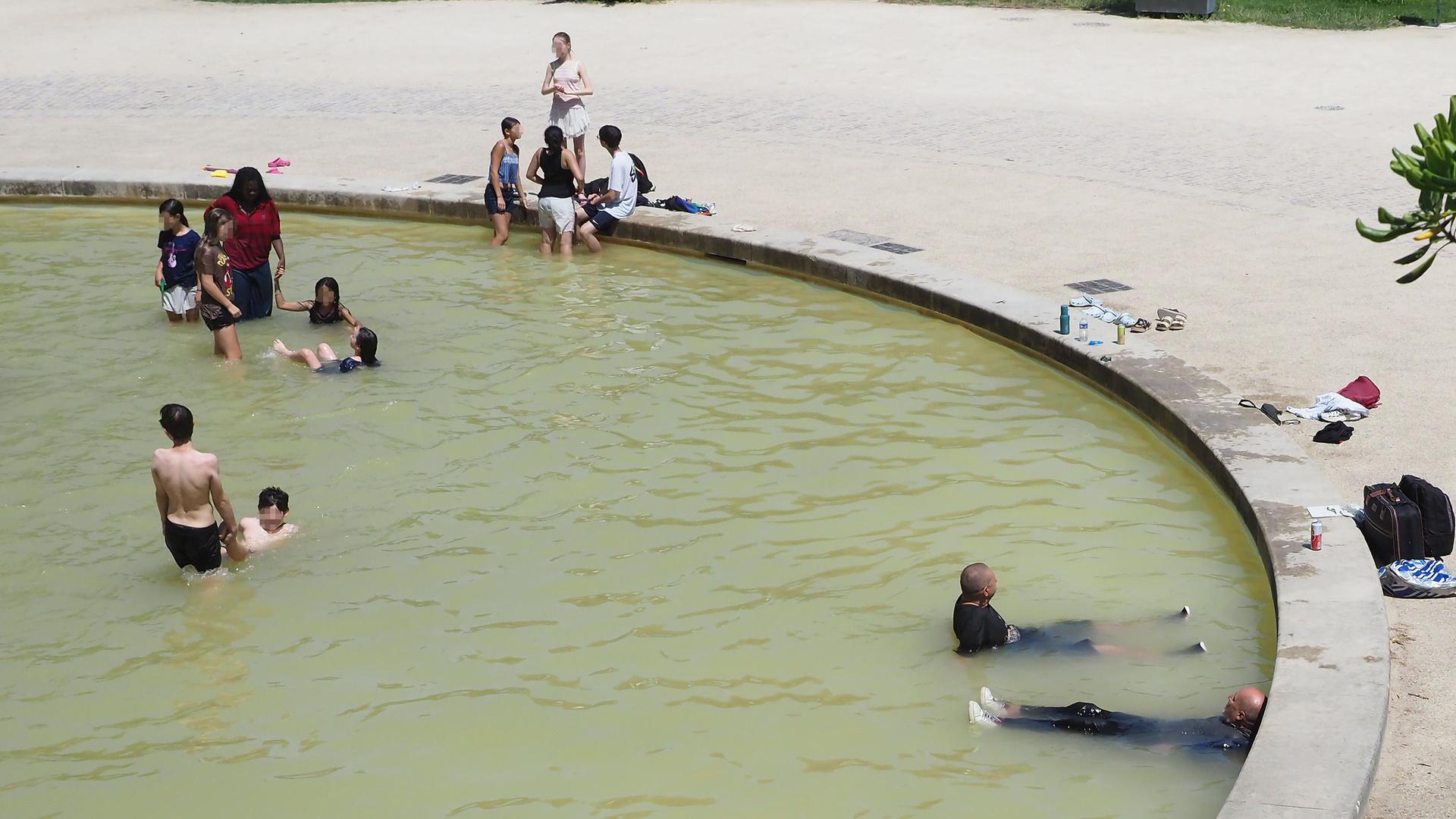 In einem Brunnen sitzen viele Menschen im Wasser. Einige tragen noch ihre Kleidung. In einem Brunnen sitzen viele Menschen im Wasser. Einige tragen noch ihre Kleidung.