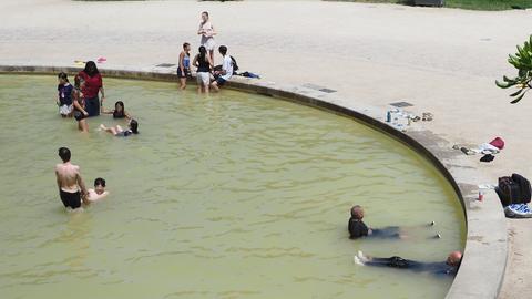 In einem Brunnen sitzen viele Menschen im Wasser. Einige tragen noch ihre Kleidung.
