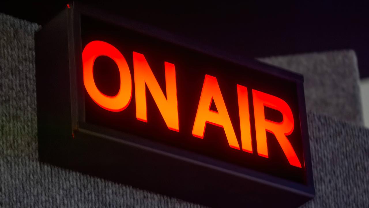 Ein rechteckiges ON AIR-Schild beleuchtet das Aufnahmestudio. Der leuchtend rote Schriftzug hebt sich von dem schwarzen Hintergrund ab. 