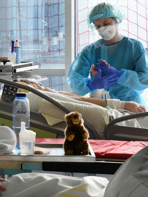 Auf der Covid-Station, einem Bereich der Operativen Intensivstation vom Universitätsklinikum Leipzig, steht eine Physiotherapeutin am Bett einer Patientin.