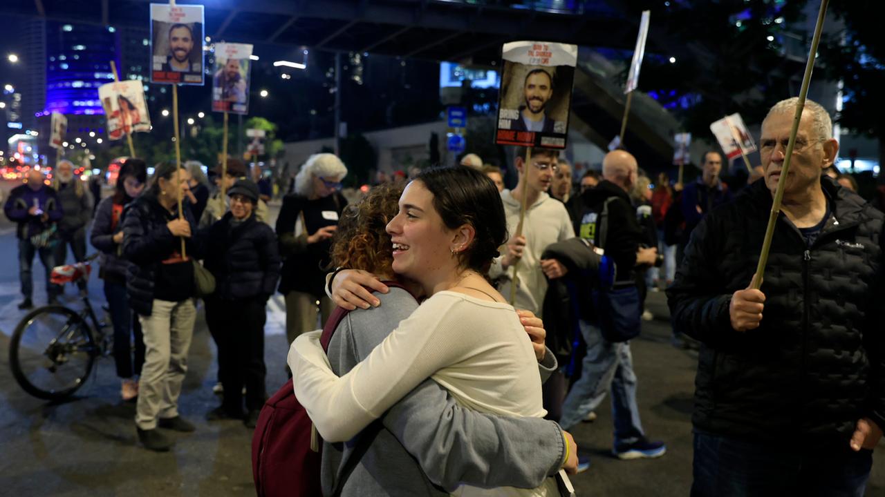 Menschen reagieren erfreut über die Meldung einer möglichen Waffenruhe und umarmen sich auf einer Demo in Tel Aviv. 