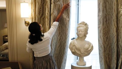 Eine Mitarbeiterin öffnet den wertvollen Vorhang in einem Zimmer des Hotel de Crillon in Paris, 2020.