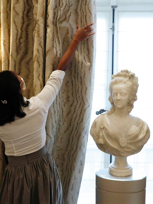 Eine Mitarbeiterin öffnet den wertvollen Vorhang in einem Zimmer des Hotel de Crillon in Paris, 2020.