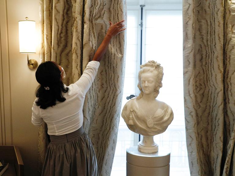 Eine Mitarbeiterin öffnet den wertvollen Vorhang in einem Zimmer des Hotel de Crillon in Paris, 2020.
