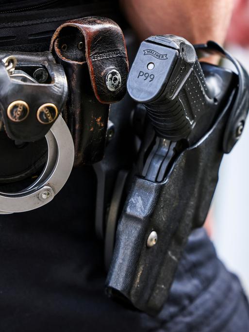 Ein Polizeibeamter trägt seine Dienstwaffe Walther P99 und Handschellen am Gürtel seiner Uniform. 