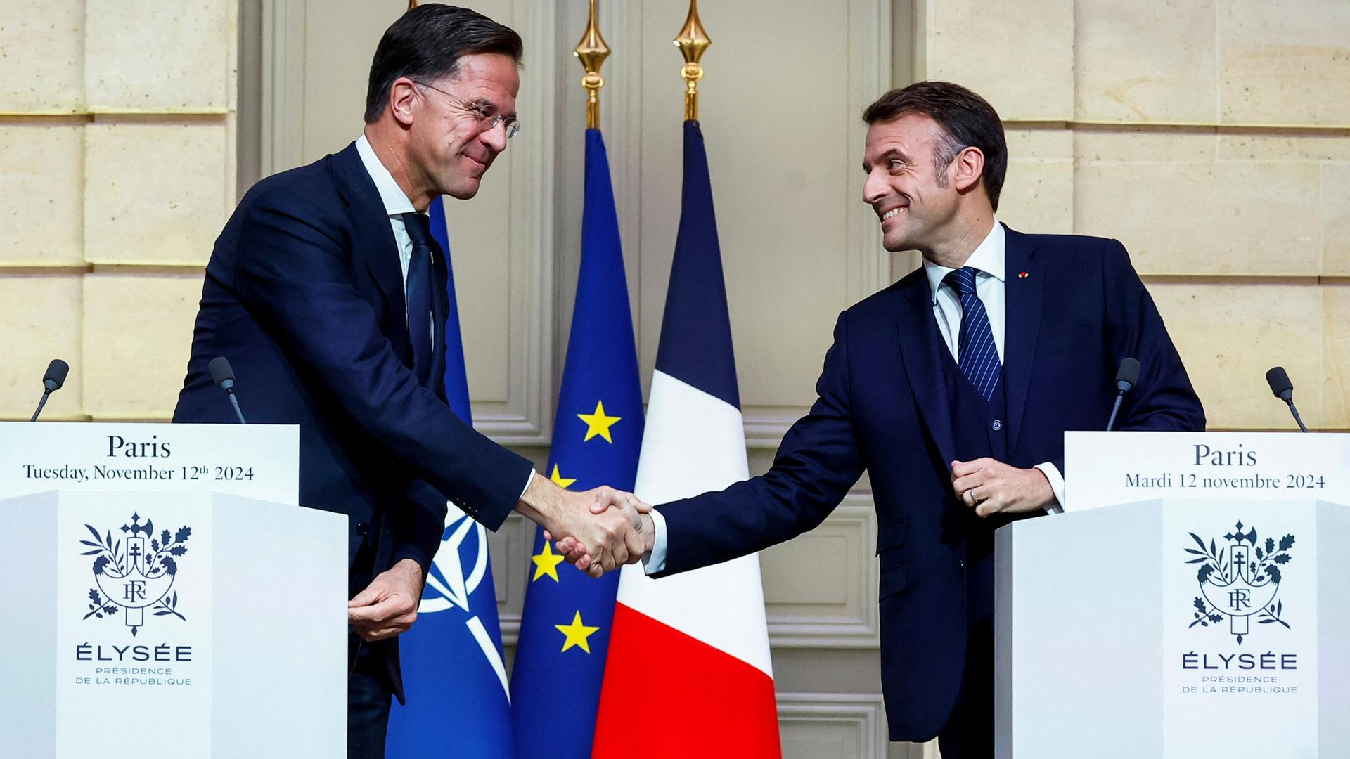 NATO-Generalsekretär Rutte und Frankreichs Präsident Macron schütteln sich die Hände.