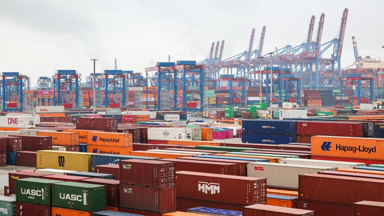 Bunte Container reihen sich aneinander auf dem Containerterminal Burchardkai (CTB) der Hamburger Hafen und Logistik AG HHLA im Hamburger Hafen. Im hintergrund sind die typischen blauen und roten Krähne sichtbar.