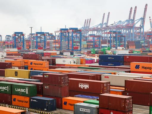 Bunte Container reihen sich aneinander auf dem Containerterminal Burchardkai (CTB) der Hamburger Hafen und Logistik AG HHLA im Hamburger Hafen. Im hintergrund sind die typischen blauen und roten Krähne sichtbar.