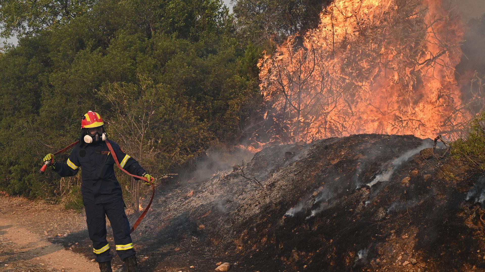 Ein Feuerwehrmann versucht bei Athen in Griechenland, einen Brand zu löschen.