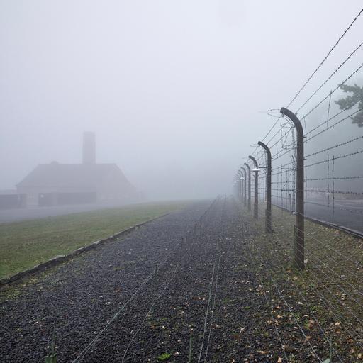 Rekonstruierter Lagerzaun mit Krematorium im Nebel in der Gedenkstätte des ehemaligen KZ Buchenwald.