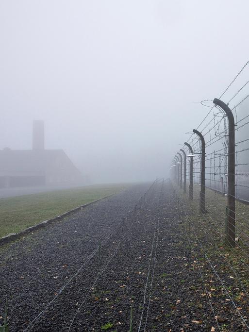 Rekonstruierter Lagerzaun mit Krematorium im Nebel in der Gedenkstätte des ehemaligen KZ Buchenwald.