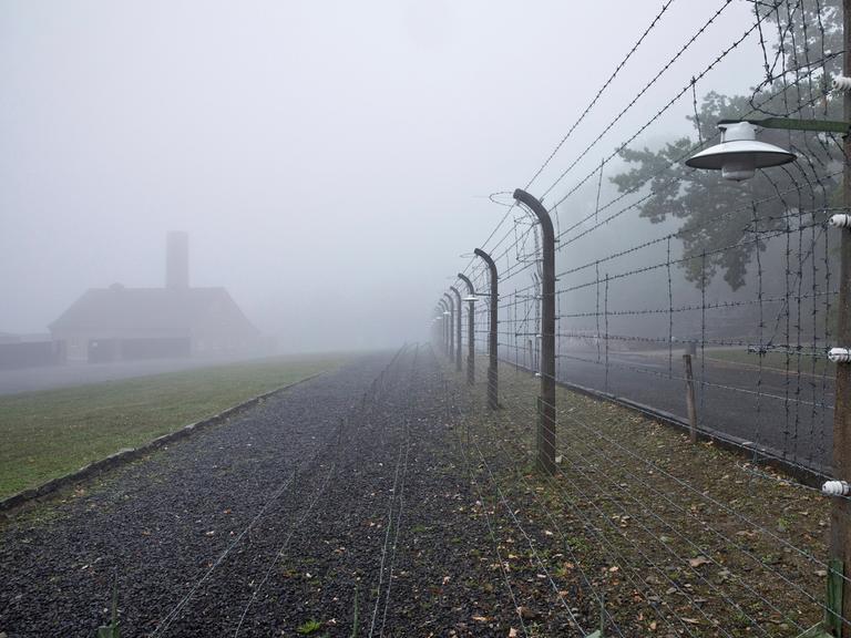 Rekonstruierter Lagerzaun mit Krematorium im Nebel in der Gedenkstätte des ehemaligen KZ Buchenwald.