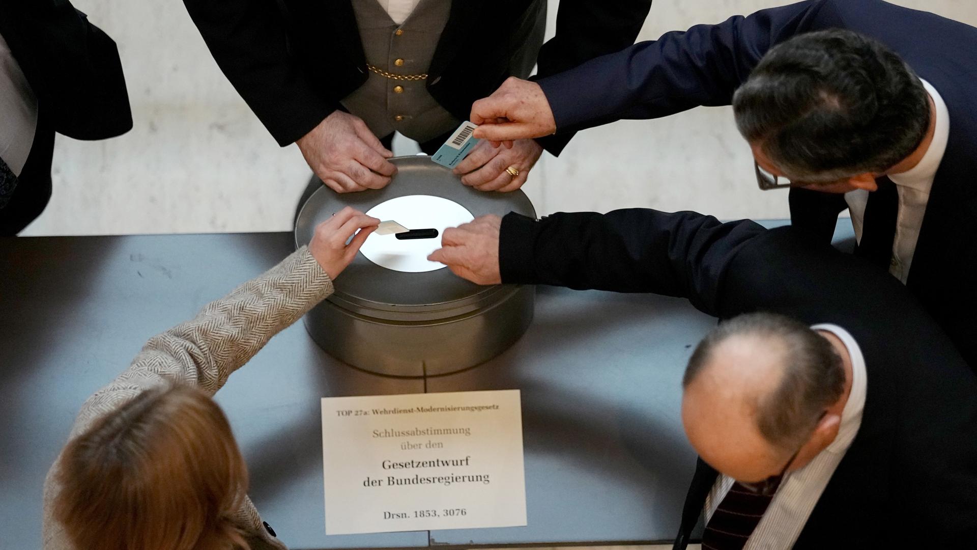 Bundeskanzler Friedrich Merz (CDU, unten r) gibt bei einer namentlichen Abstimmung über das Gesetz für einen neuen Wehrdienst seine Stimmkarte im Bundestag ab.