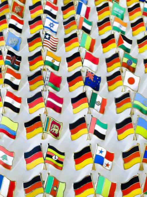 Pins mit den kombinierten Nationalflaggen von Deutschland und vielen verschiedenen Staaten stehen auf einem Tisch in Berlin.