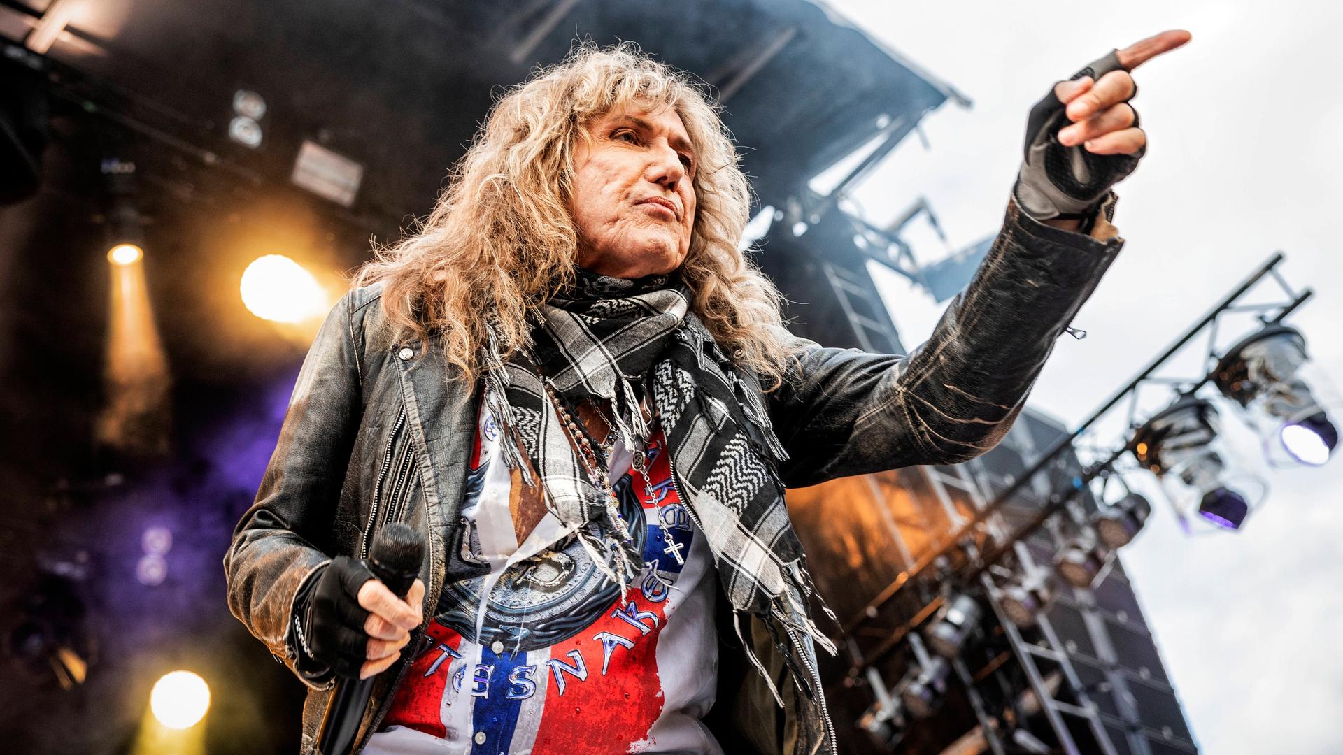 David Coverdale in Aktion auf der Bühne, er zeigt mit der linken Hand in das Publikum.
