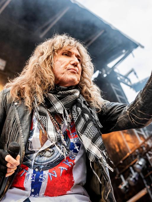 David Coverdale in Aktion auf der Bühne, er zeigt mit der linken Hand in das Publikum.