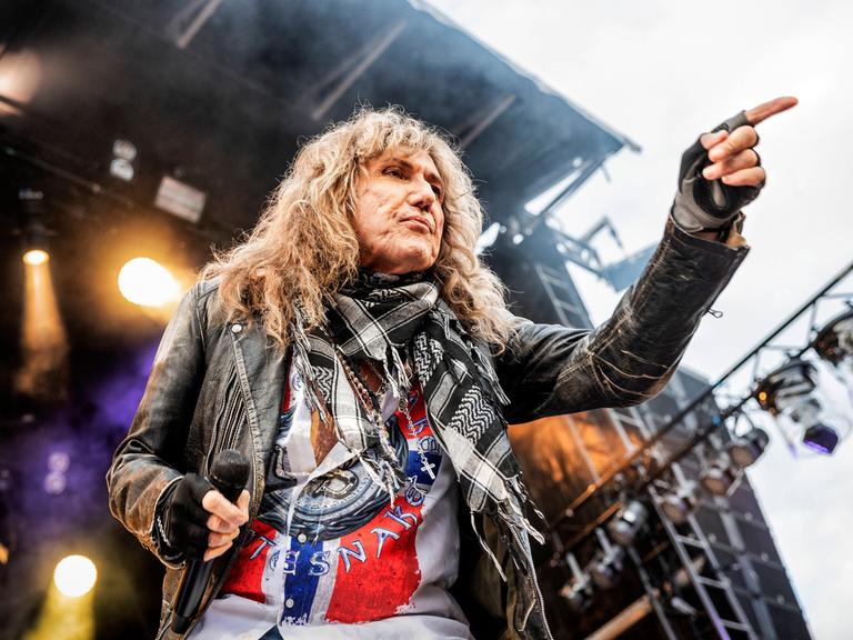 David Coverdale in Aktion auf der Bühne, er zeigt mit der linken Hand in das Publikum.