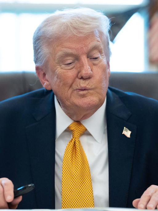 US-Präsident Trump sitzt am Schreibtisch im Oval Office und zieht eine Grimasse.