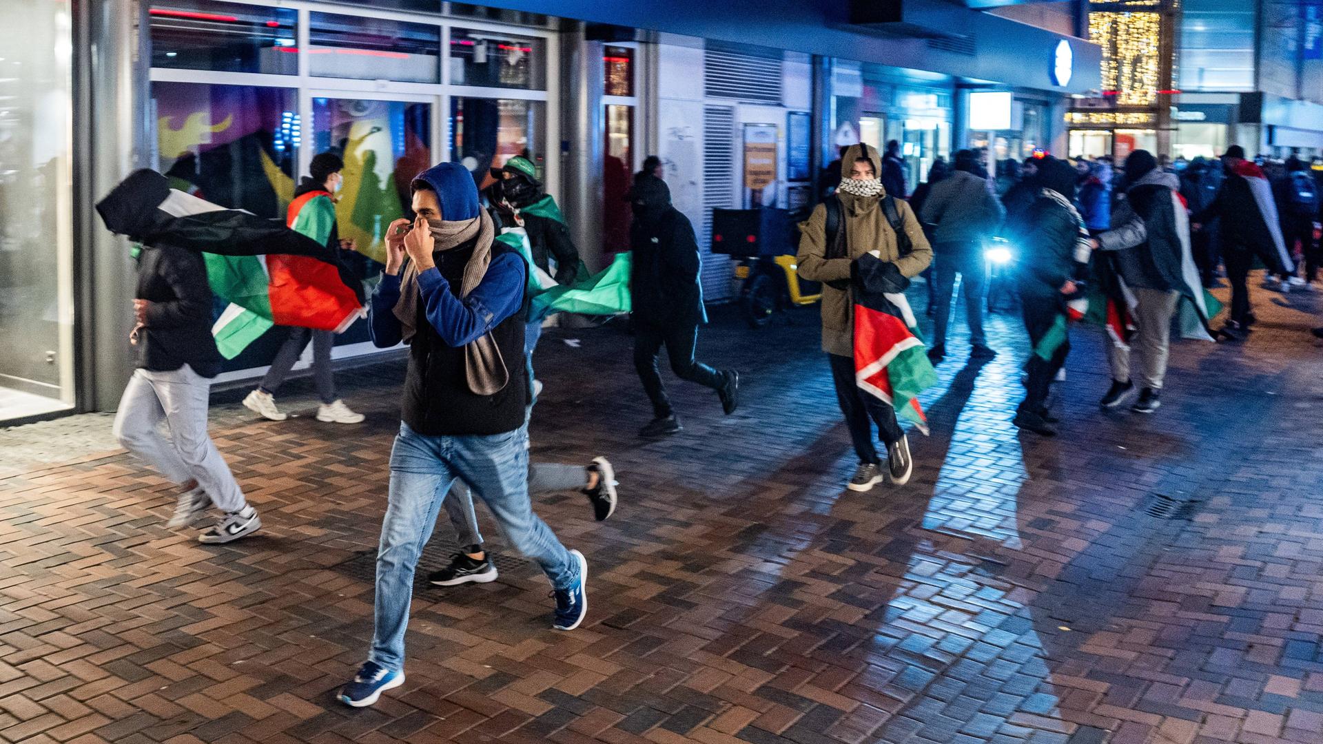 Demonstranten laufen mit palästinensischen Fahnen bei einer pro-palästinensischen Demonstration während des Spiels Ajax - Maccabi Tel-Aviv am Anton de Komplein.