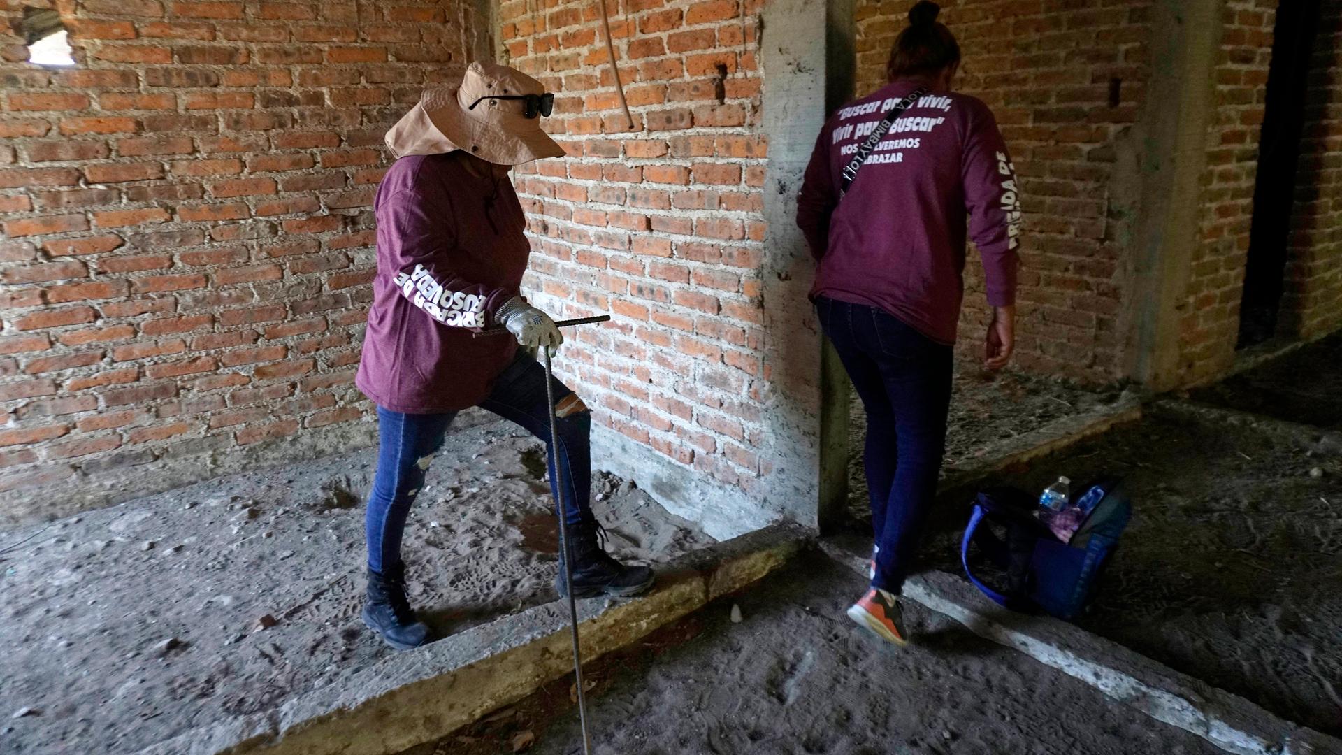 Zwei Personen untersuchen das Grundstück, auf dem die Leichen gefunden wurden. Zwei Personen untersuchen das Grundstück, auf dem die Leichen gefunden wurden.