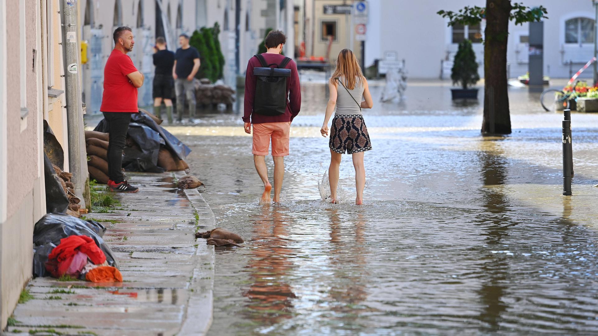 Ein Paar watet barfuss durch das Hochwasser in der Altstadt von Passau.