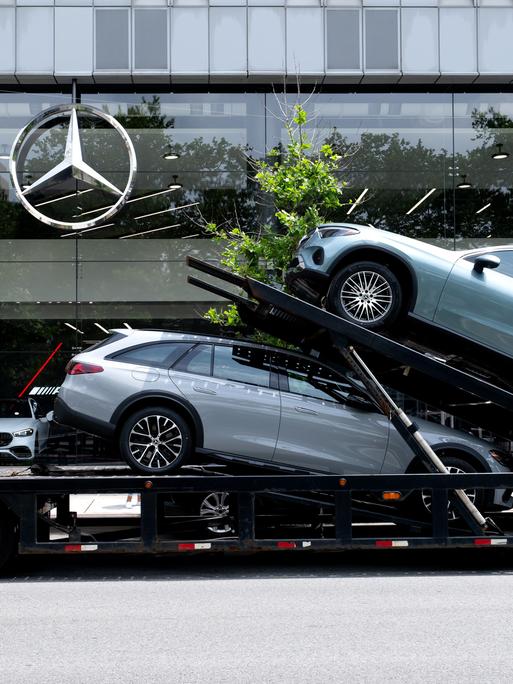 Ein Autotransporter mit Neuwagen von Mercedes-Benz steht vor einem Autohaus in Manhattan.