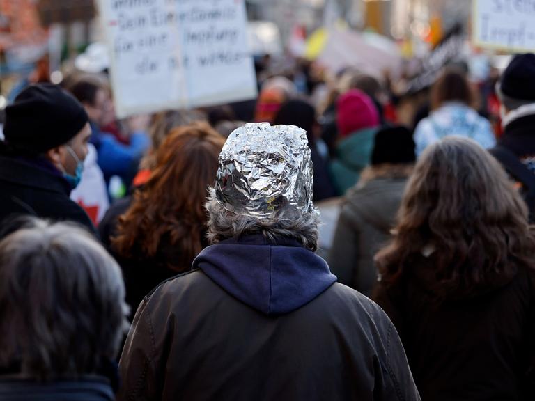 Eine Person mit einem Aluhut auf einer Demonstration gegen die Impflicht.