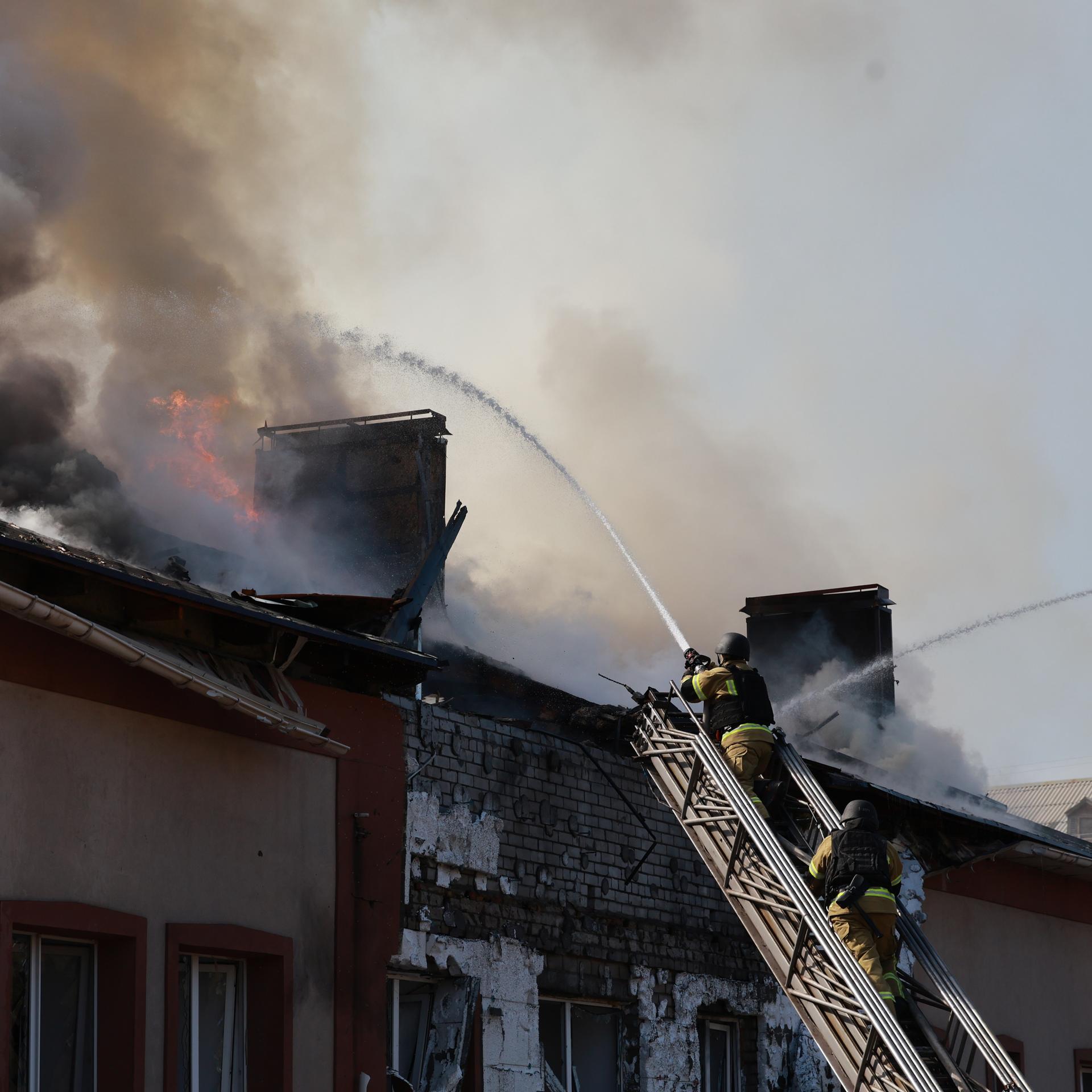Rettungskräfte versuchen, ein Feuer in einem Gebäude zu löschen, das nach einem russischen Drohnenangriff auf Saporischschja in der Ukraine brennt.