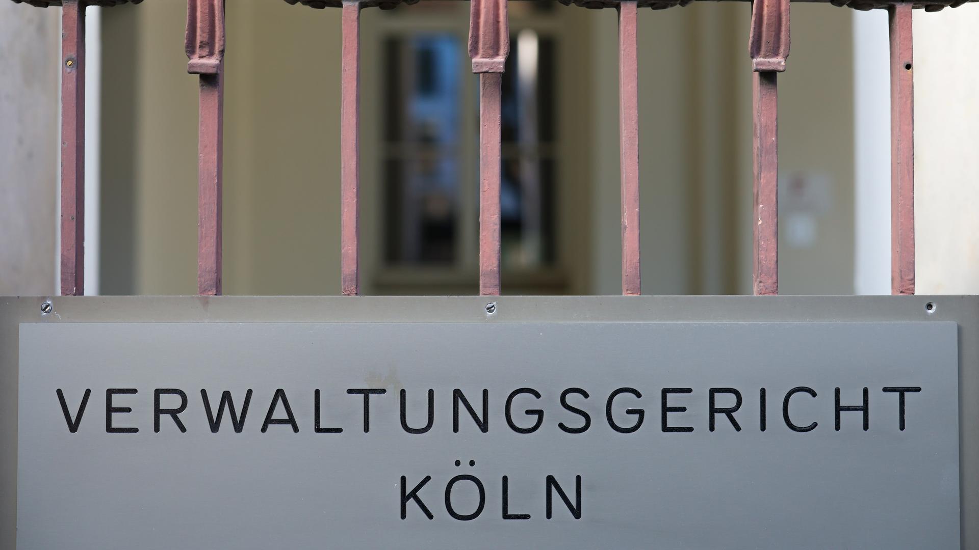 Ein Schild hängt am Eingang des Verwaltungsgerichts in Köln. Darauf steht: "Verwaltungsgericht Köln".