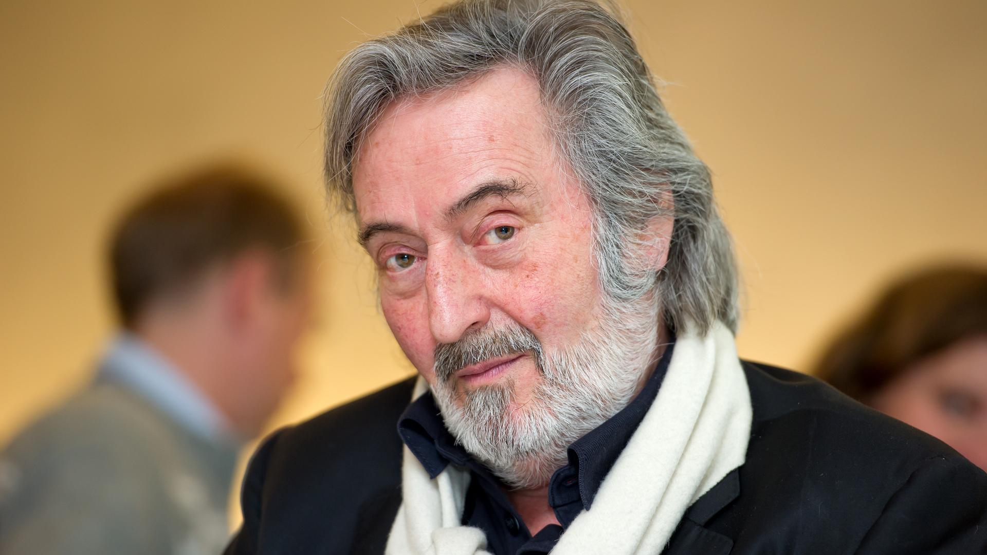 Der Regisseur Helmut Dietl steht im Jahr 2011 während einer Pressekonferenz der FilmFernsehFonds Bayern GmbH (FFF) in München in einem schwarzen Jackett und weißem Schal in einem Raum und schaut in die Kamera.